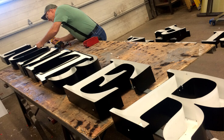 Fabricator Assembling Channel Letters in a sign shop