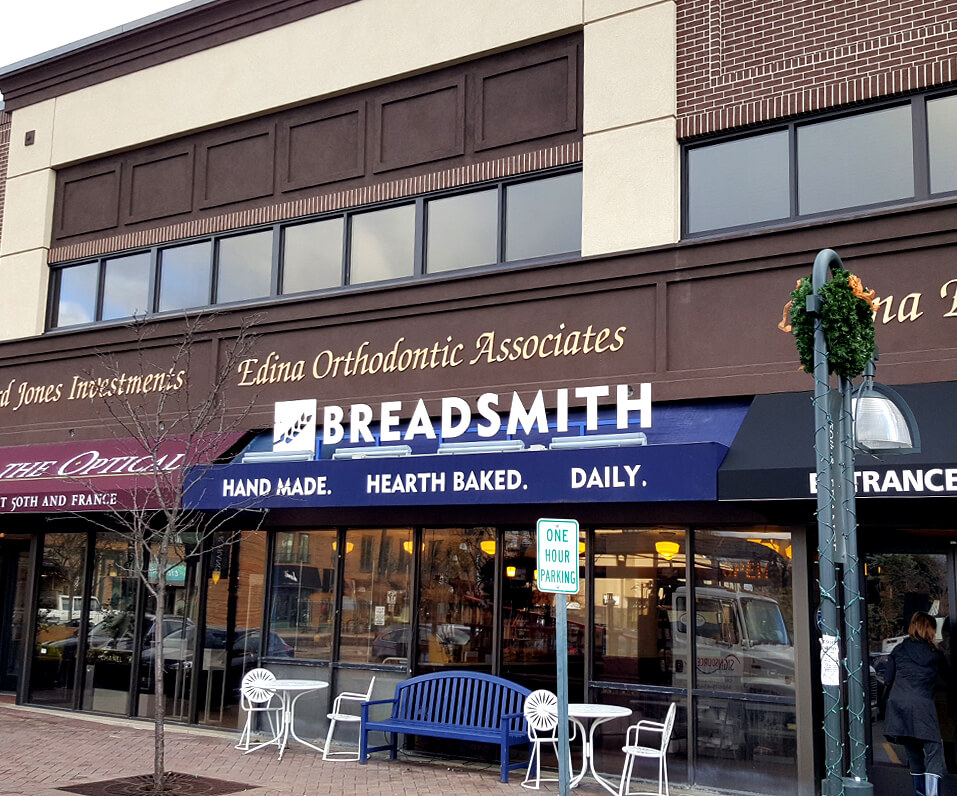 50th and France Storefront showcasing multiple awning types Breadsmith letters on top of blue awning