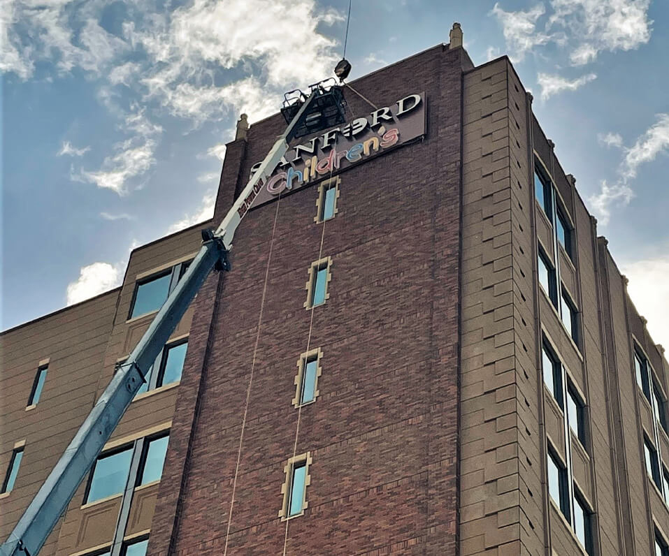 Indigo Signs installing Channel letters on top floor of Sanford Childrens hospital in Fargo ND